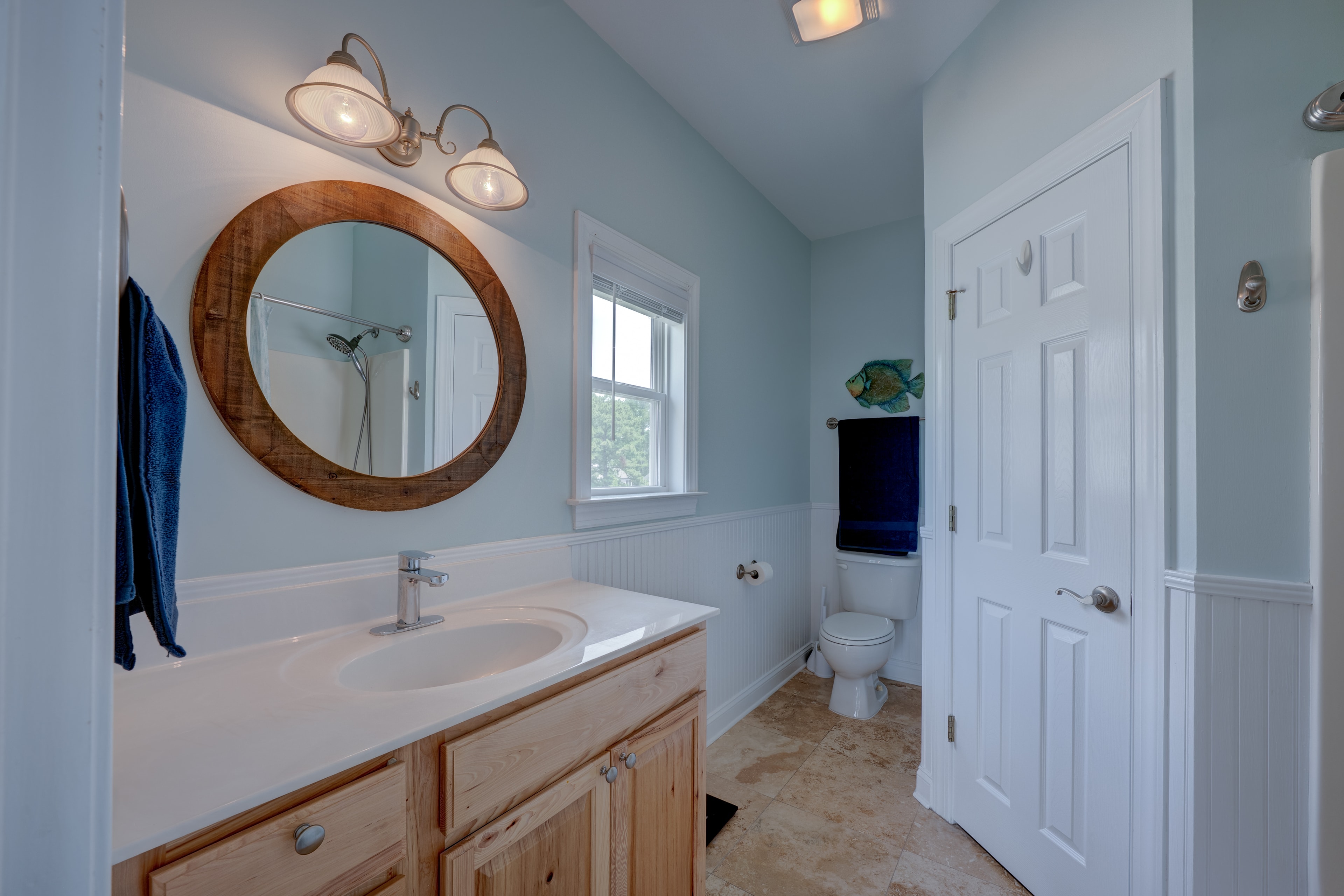 Master bath with round wood mirror and walk-in closet